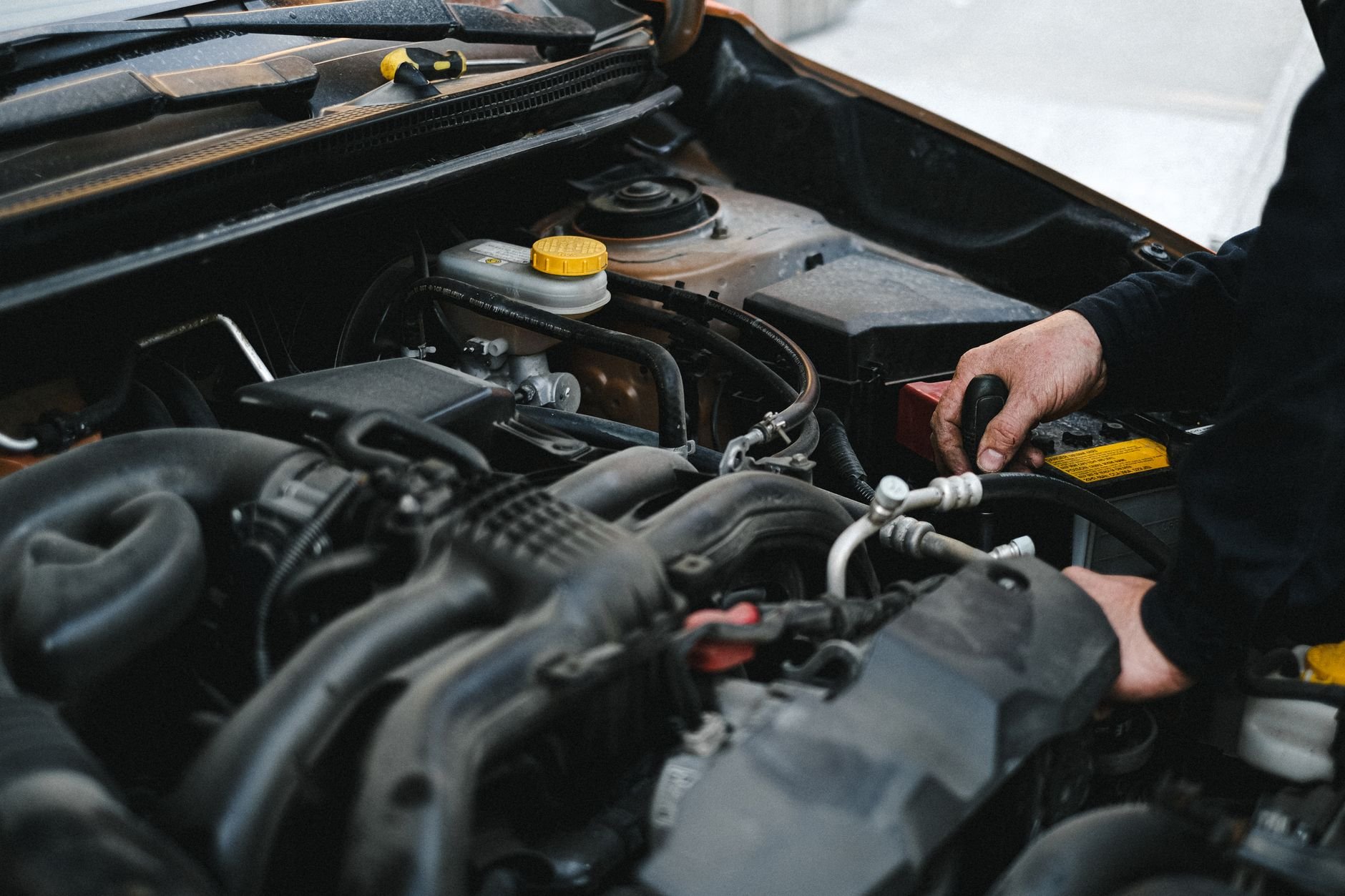 Close-up of a mechanic's hands working on a car engine, showcasing repair work.